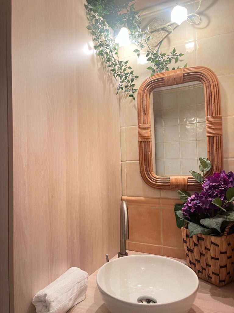 Baño con lavabo y espejo de mimbre