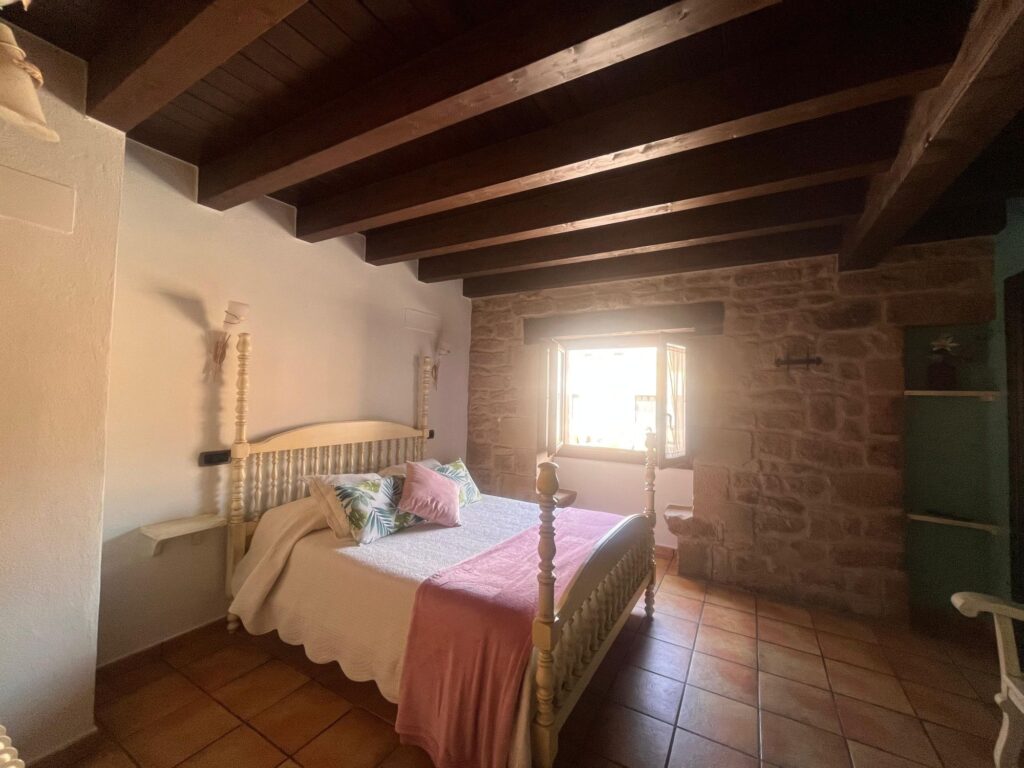 Habitación doble con vigas de madera y pared de piedra