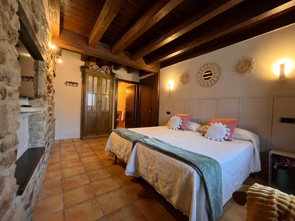 Habitación con dos camas y pared de piedra